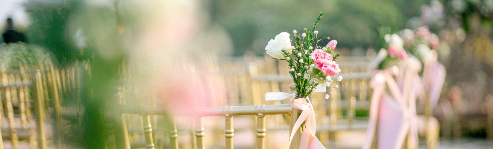 gold chiavari chair at wedding with small pink and white floral arrangement attached